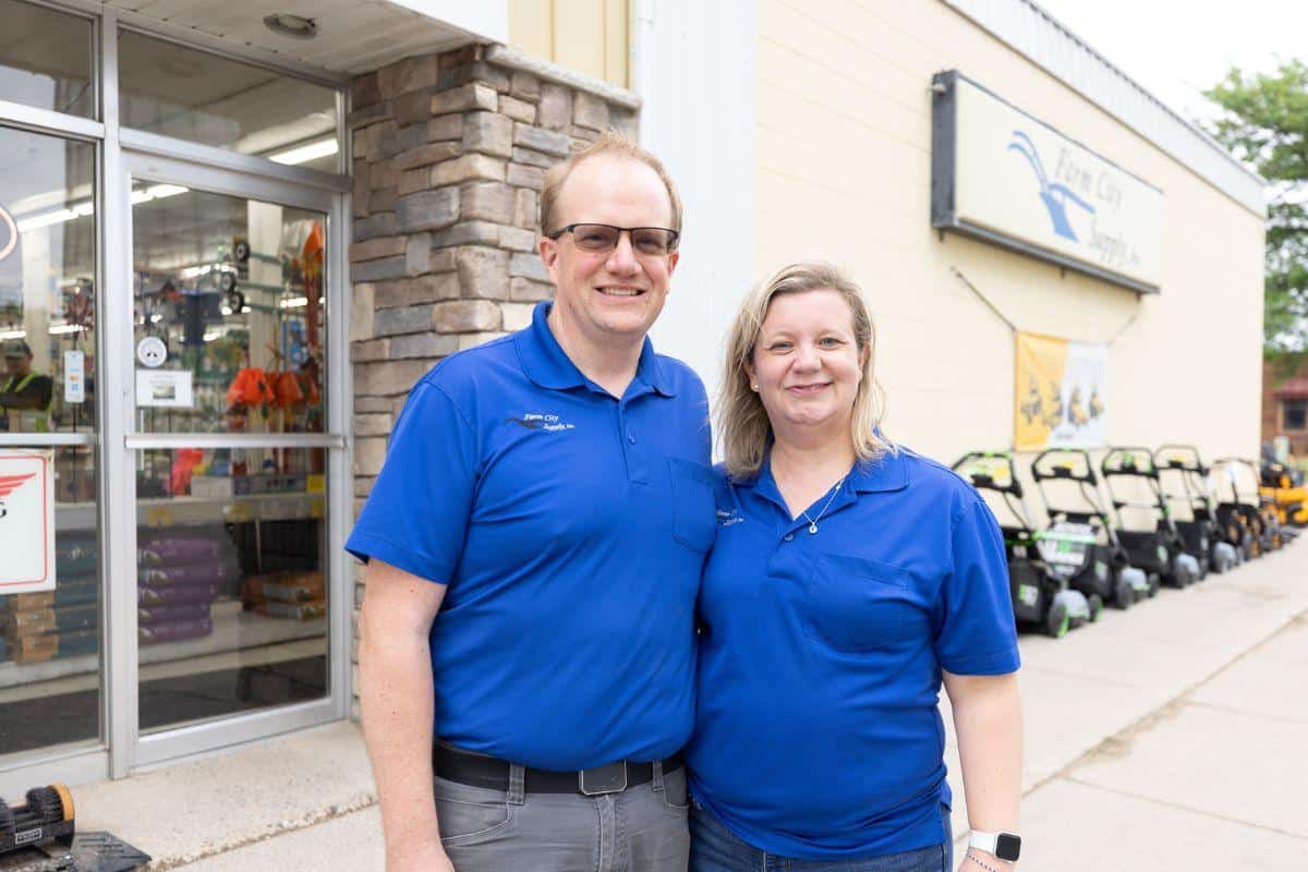 Farm City Supply owners standing outside the store entrance, smiling and welcoming customers.
