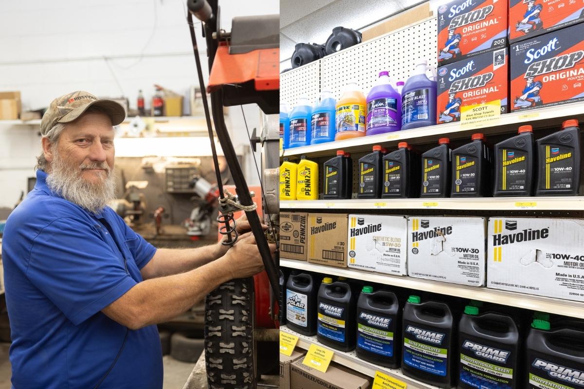 Farm City Supply team member working on equipment in the repair shop beside motor oil and maintenance supplies.