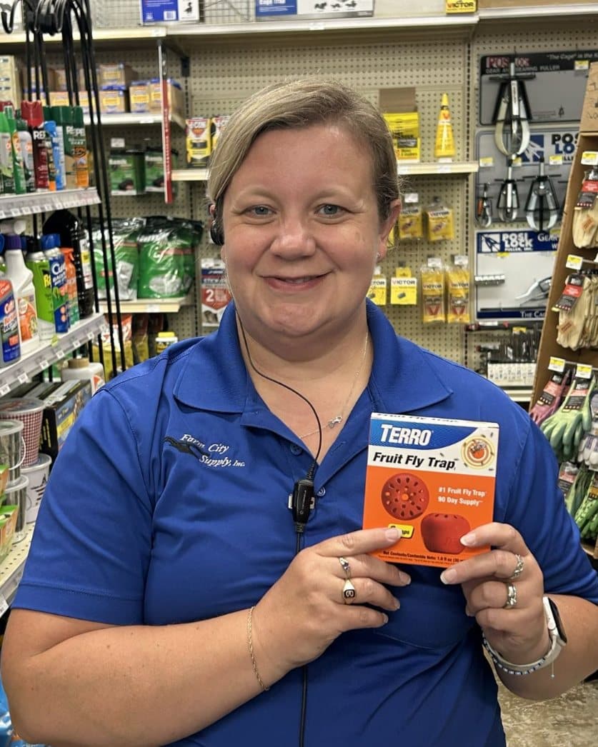 Farm City Supply employee holding a TERRO Fruit Fly Trap in the store's pest-control aisle.