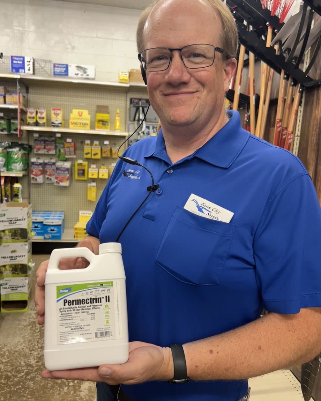 Farm City Supply employee holding a container of Permectrin II insecticide and animal-premise spray.
