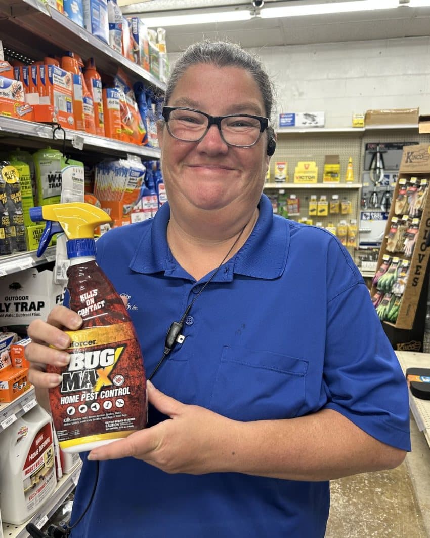 Farm City Supply employee holding a spray bottle of Enforcer Bug Max Home Pest Control.