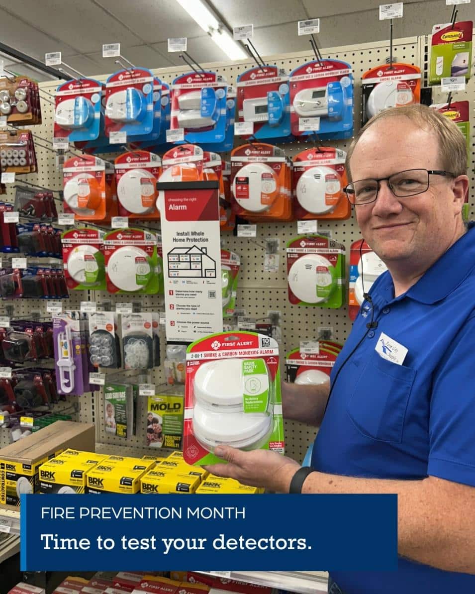 Farm City Supply employee holding a bag of Spectracide Triazicide Insect Killer for Lawns in the pest-control aisle.